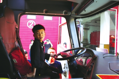 小英杰被消防队的哥哥们抱上消防车，还握住了方向盘受访者供图